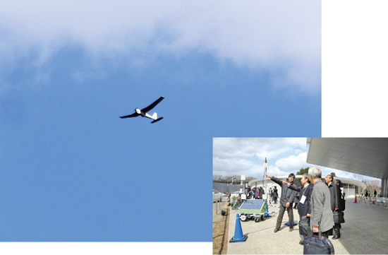 図4　自律で旋回飛行する無人飛行機とそれを見上げる公開実証実験見学者
